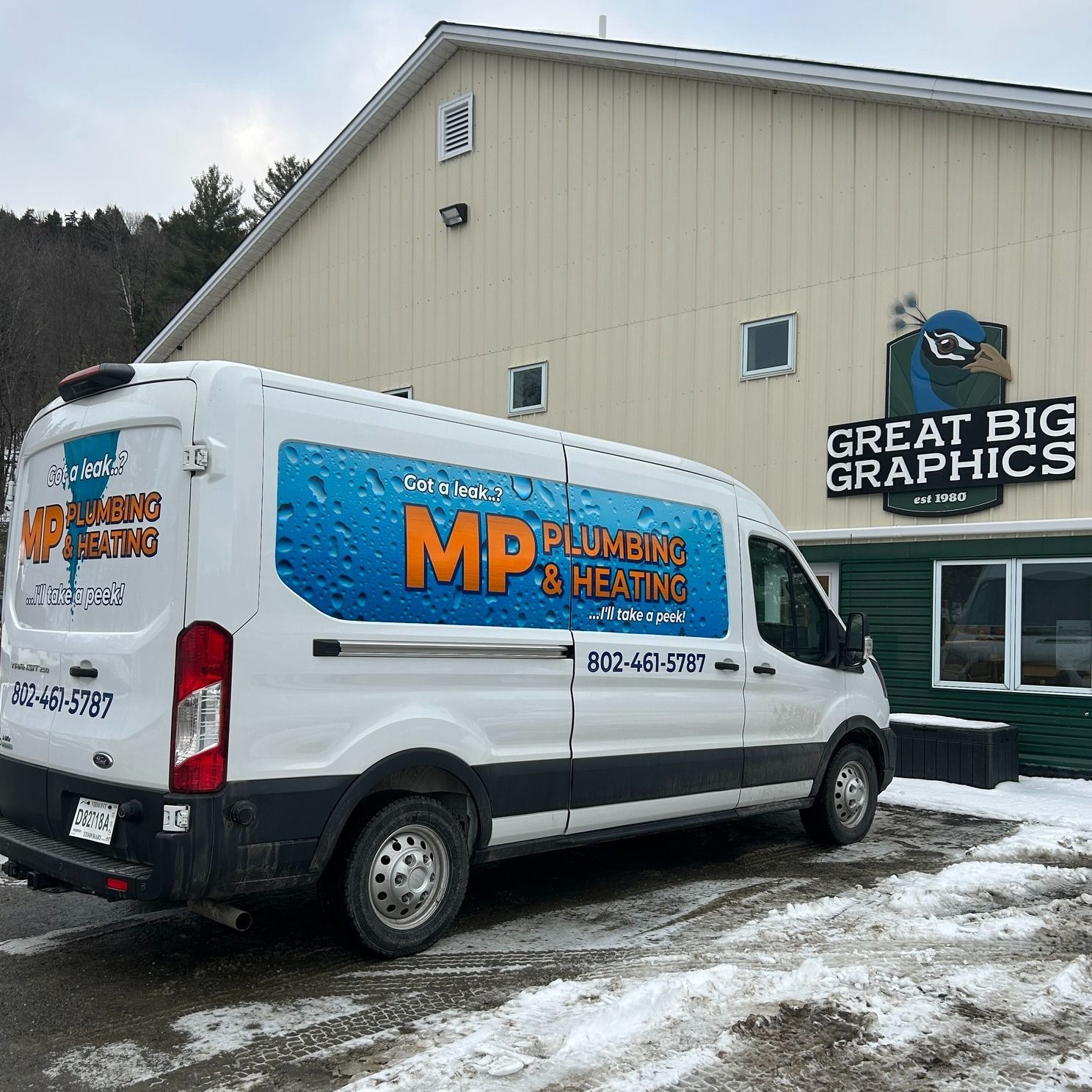 White van with "MP Plumbing & Heating" parked outside "Great Big Graphics" building; snowy ground.