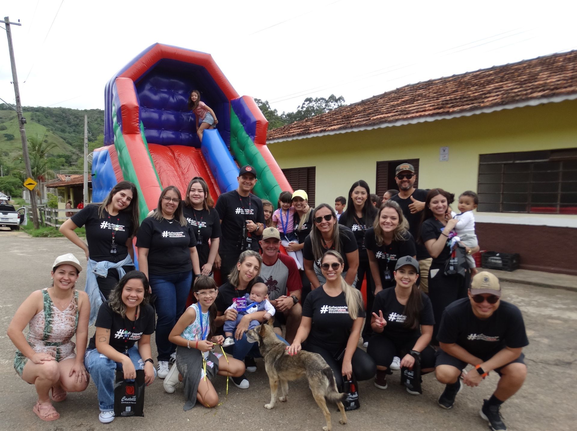 Um grupo de pessoas posa para uma foto em frente a um escorregador inflável.