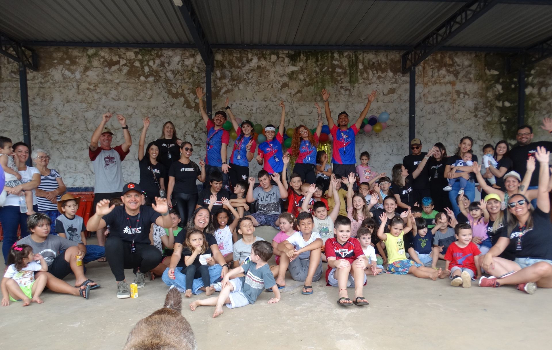 Um grupo de pessoas posa para uma foto com as mãos para cima.