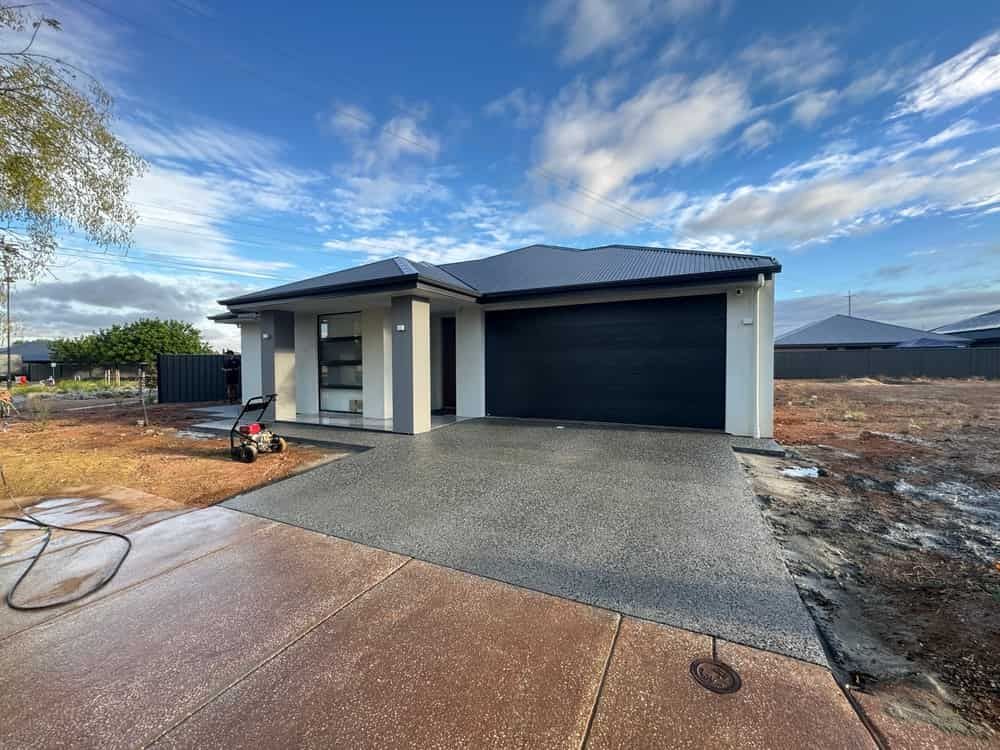 A House With a Black Garage Door and a Concrete Driveway — Bloomscapes in Lennox Head NSW