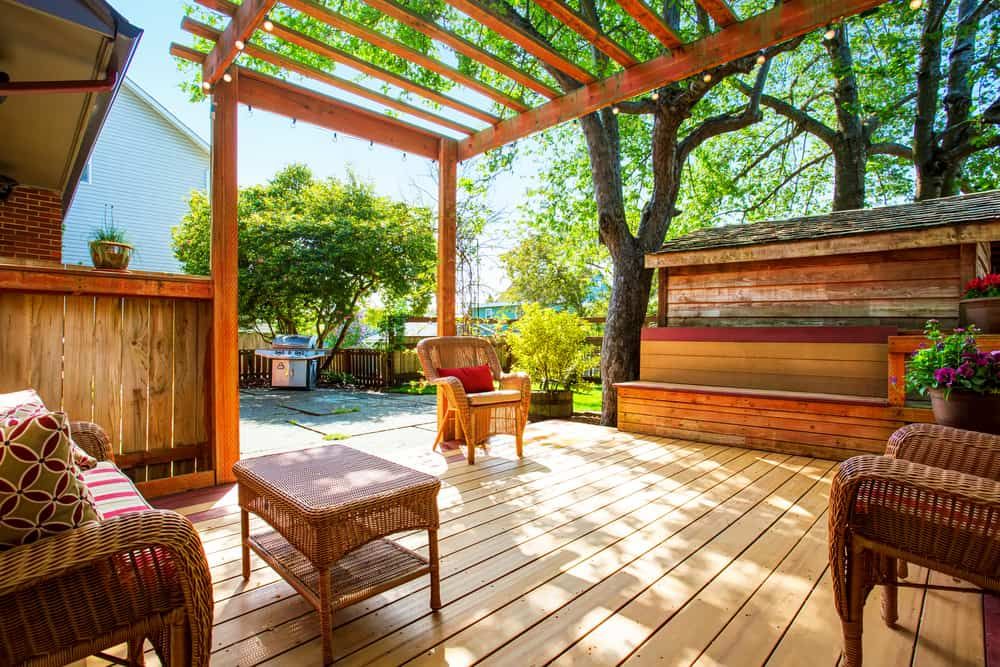 A Wooden Deck With Wicker Furniture and a Pergola — Bloomscapes in Lennox Head NSW