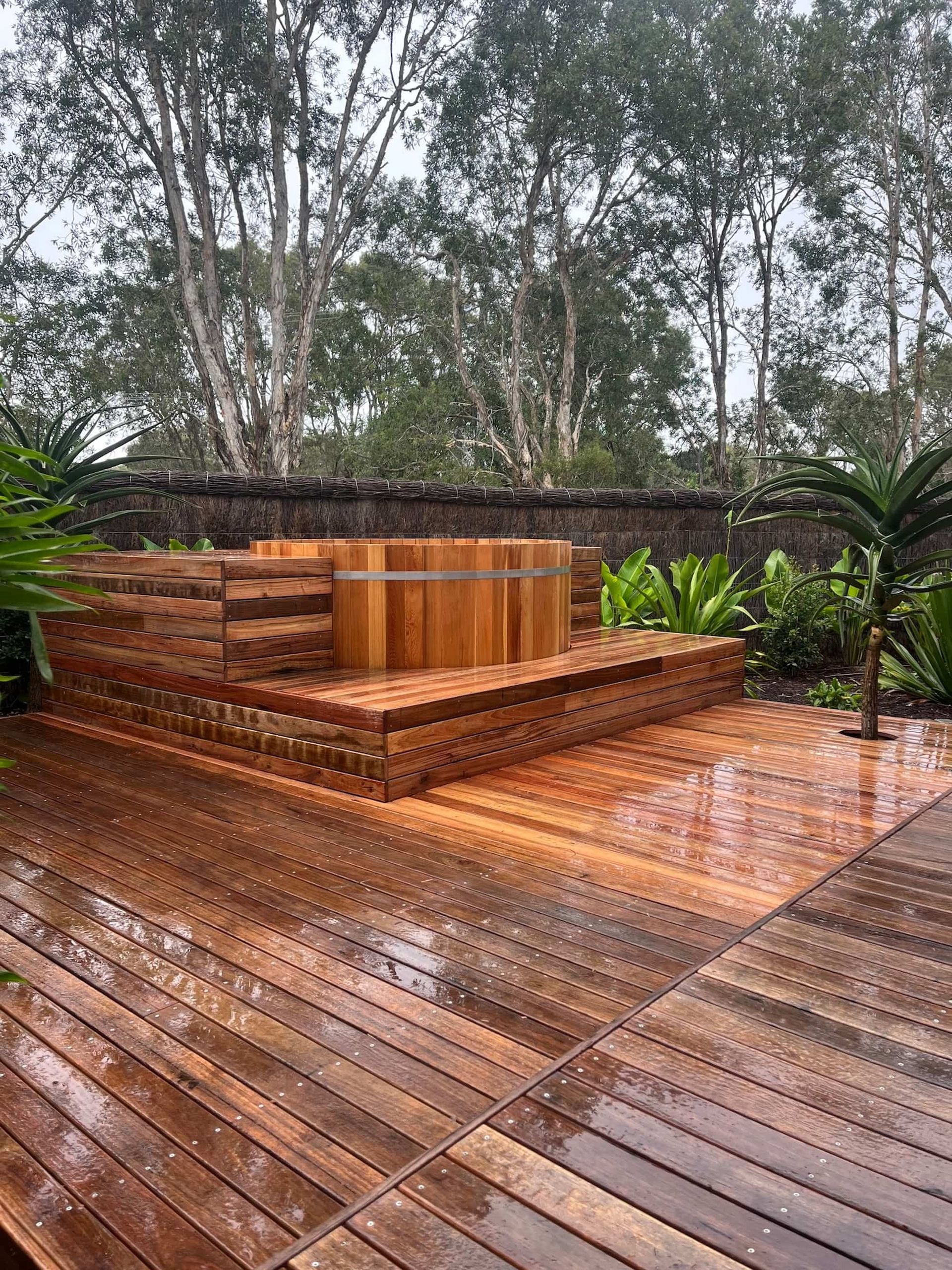 A Wooden Hot Tub is Sitting on Top of a Wooden Deck — Bloomscapes in Lennox Head NSW