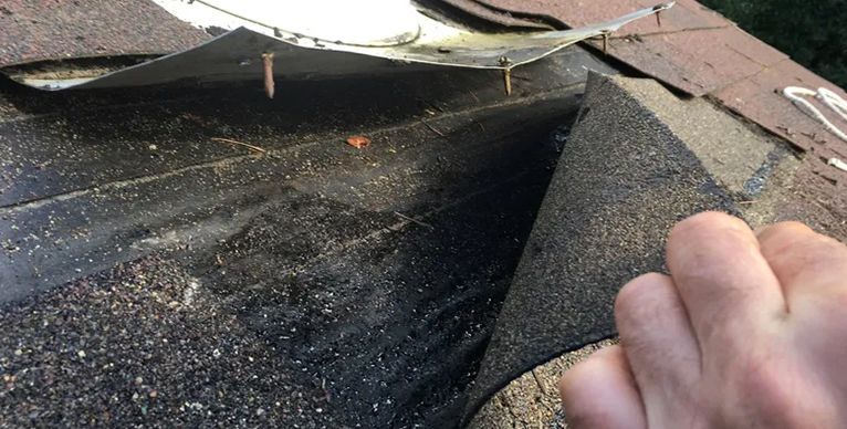 A person is holding a piece of rubber on top of a roof.