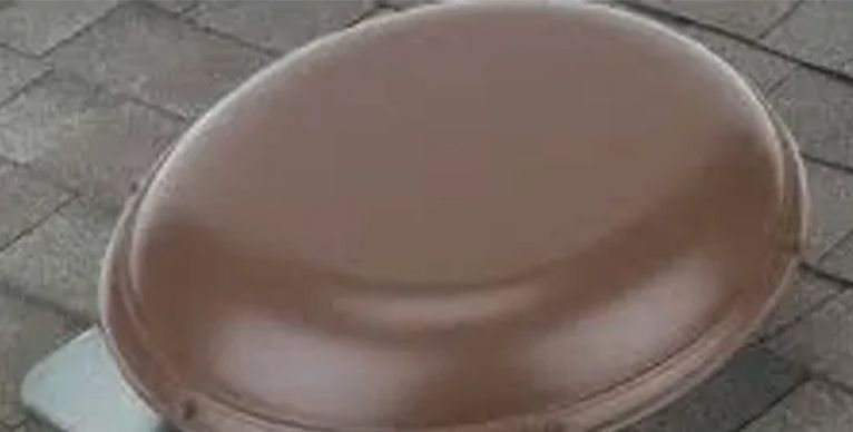 A close up of a brown toilet seat on a brick floor.