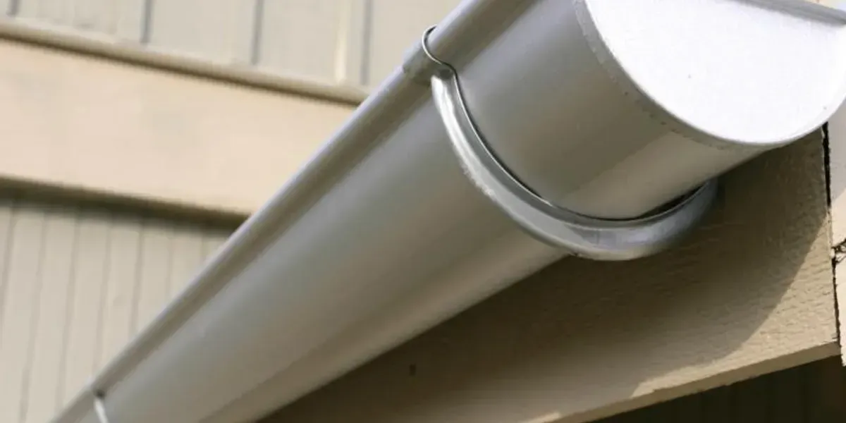 A white gutter is attached to the side of a building.