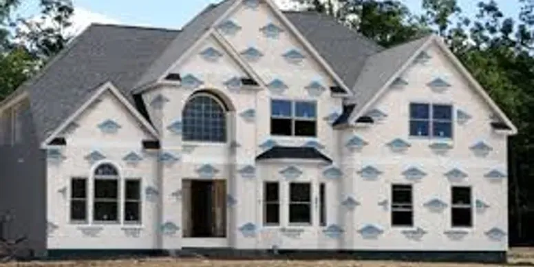 A large white house with a gray roof is being built.