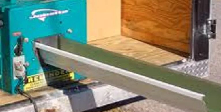 A machine is cutting a piece of metal on a conveyor belt.
