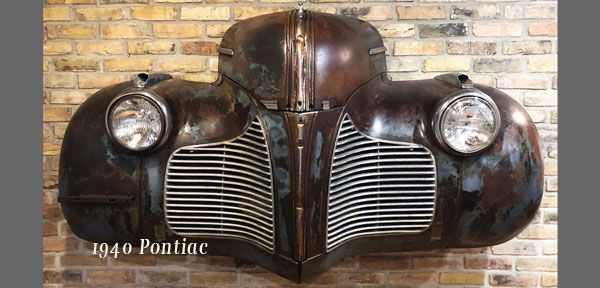 A 1940 pontiac car is hanging on a brick wall.