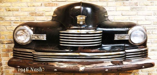 A 1946 nash car is hanging on a brick wall