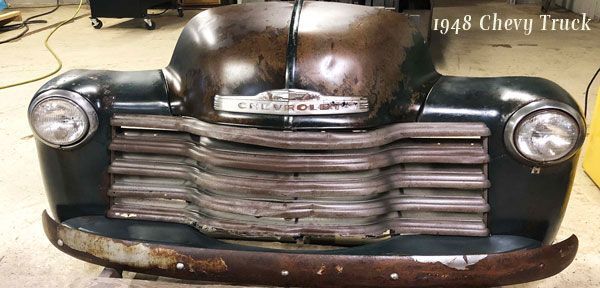 A 1948 chevy truck is sitting on a table in a garage.