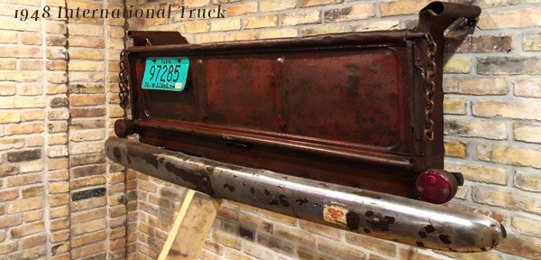 A wooden sign with a license plate on it is hanging on a brick wall.
