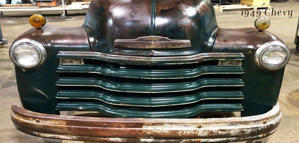 A close up of the front of an old chevrolet truck in a garage.