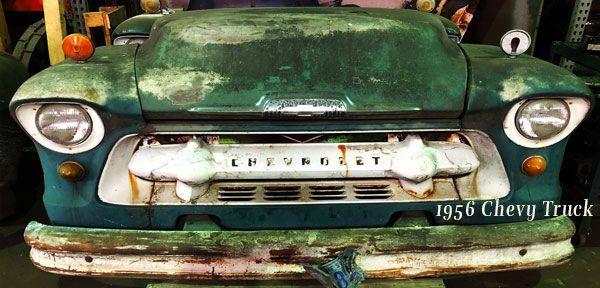 The front of an old chevrolet truck is sitting in a garage.