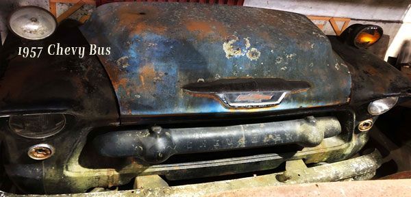 A 1957 chevy bus is sitting in a garage.
