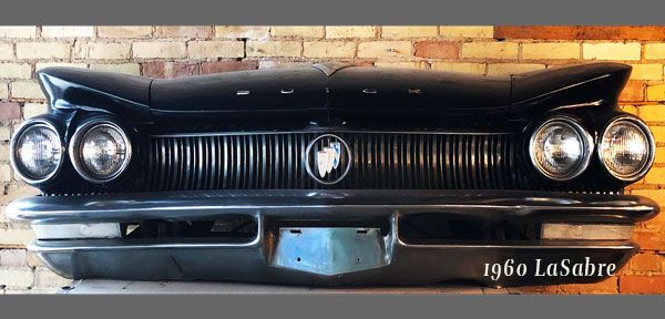 A 1960 buick la sabre is hanging on a brick wall