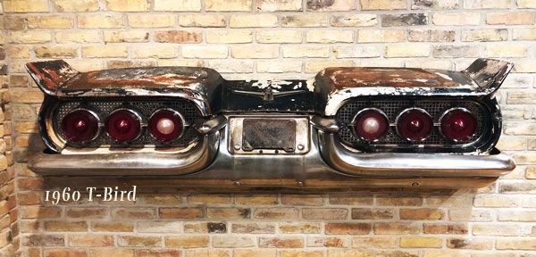 A 1960 t-bird tail light is hanging on a brick wall.