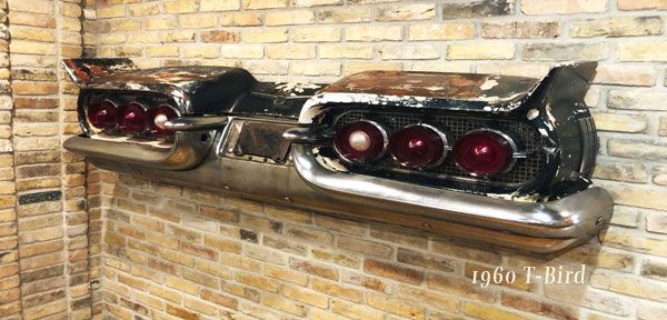 A car bumper is hanging on a brick wall.