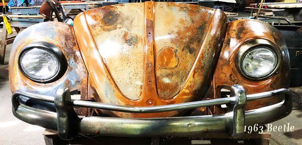A close up of a rusty volkswagen beetle in a garage.