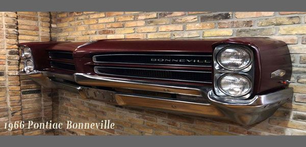 The front end of a pontiac bonneville is hanging on a brick wall.