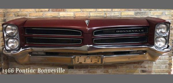A red pontiac bonneville is hanging on a brick wall.