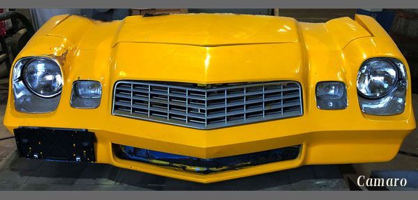 A yellow chevrolet camaro is sitting on a table.