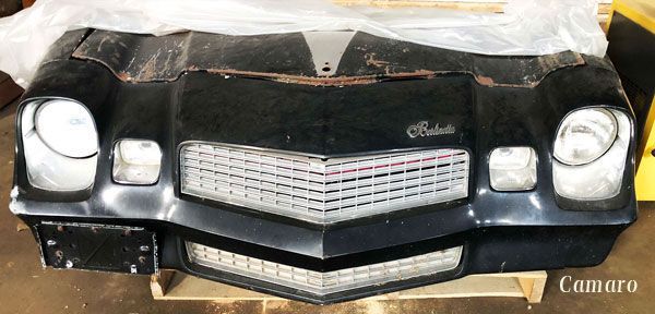 A black car bumper is sitting on top of a wooden pallet.