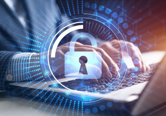 Person typing on a laptop with a digital padlock overlay, symbolizing cybersecurity.