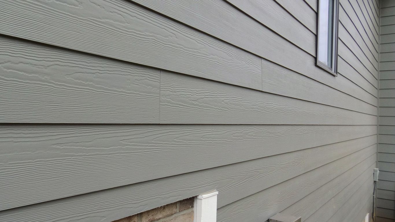 The side of a house with a gray siding and a window.