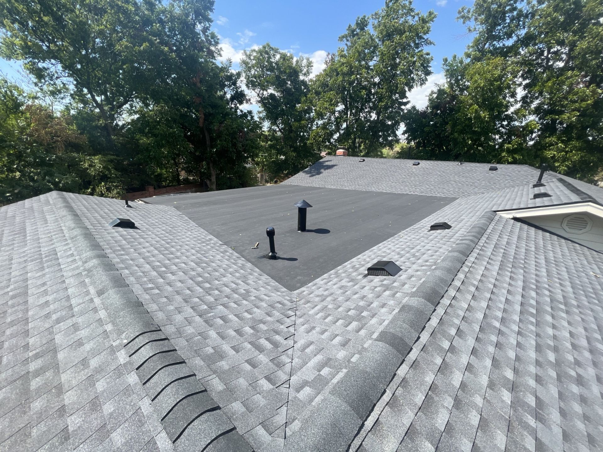 A roof with a triangle in the middle of it and trees in the background.