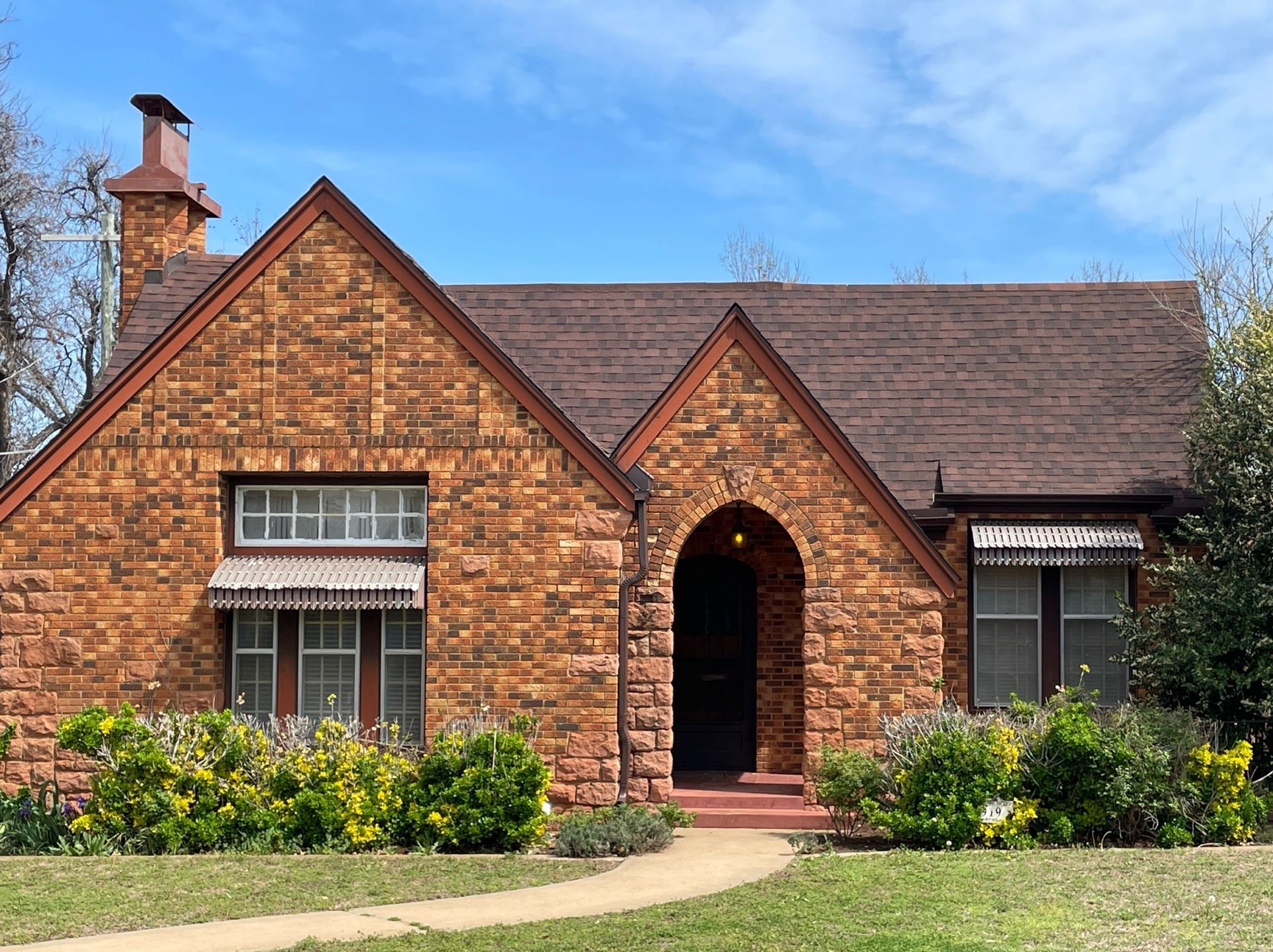 A brick house with a brown roof and a chimney