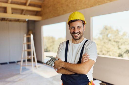 A Construction Worker Is Standing In A Room With His Arms Crossed And Smiling — Kingston, NY — T.I. Contracting A Construction Worker Is Standing In A Room With His Arms Crossed And Smiling — Kingston, NY — T.I. Contracting