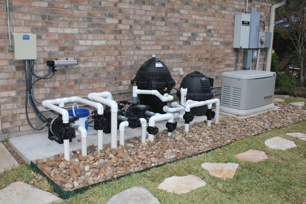 A backyard with a brick wall and a lot of pipes
