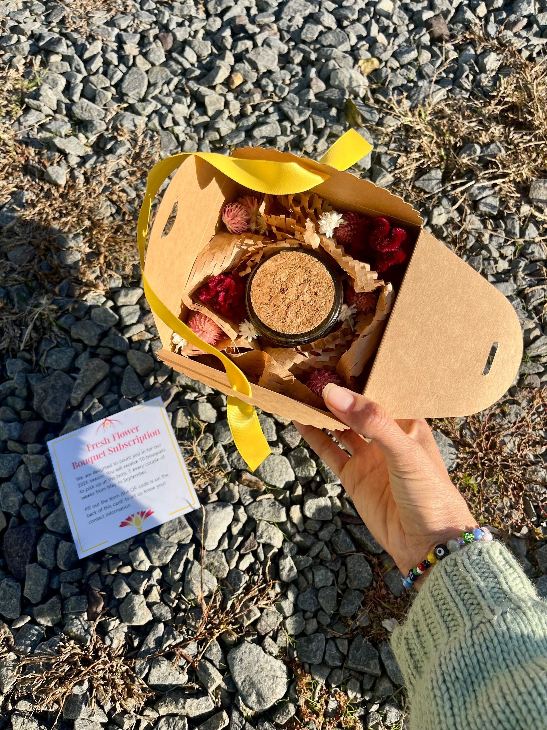 A yellow ribbon subscription box looking open from up top, where we can see the top of a dried flower jar.