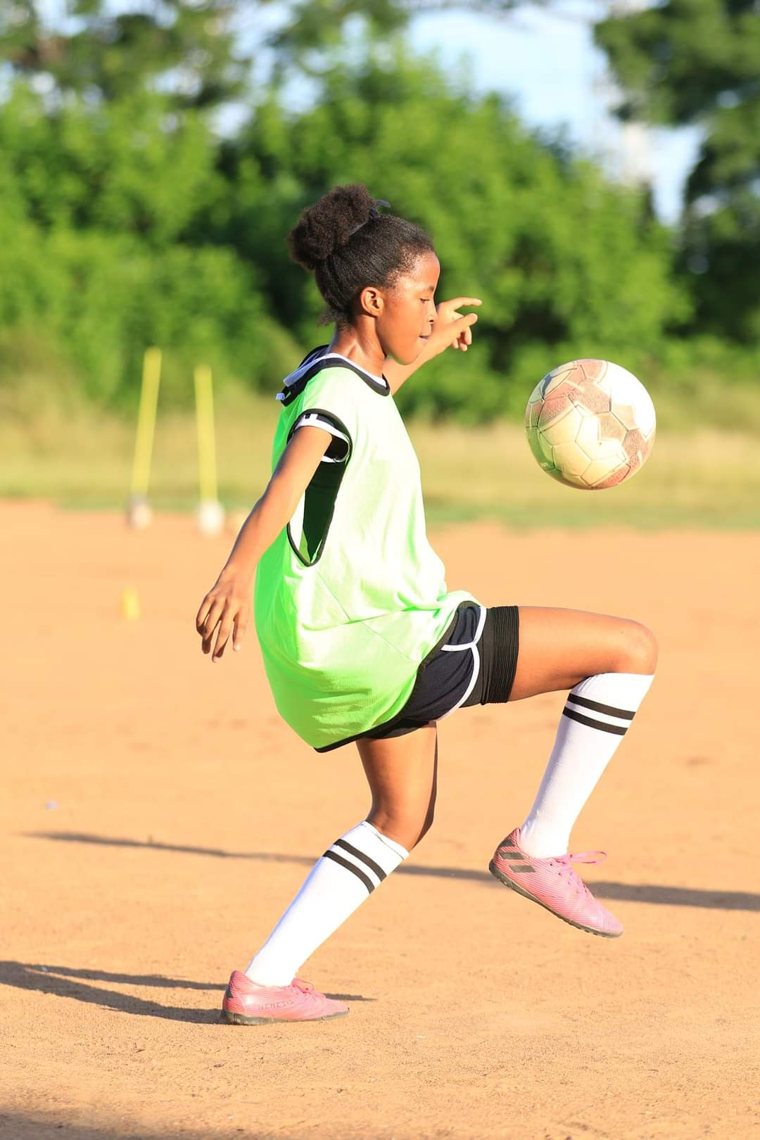 A young girl is kicking a soccer ball on a field