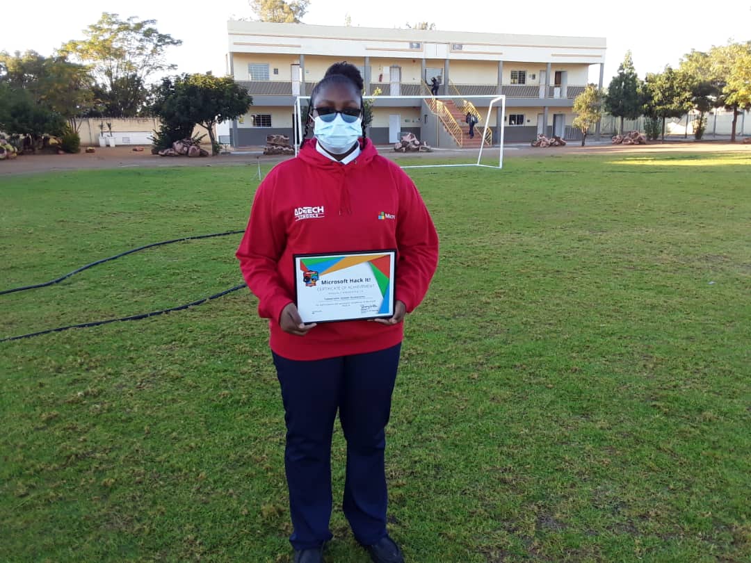 A woman wearing a mask is holding a certificate in a field.