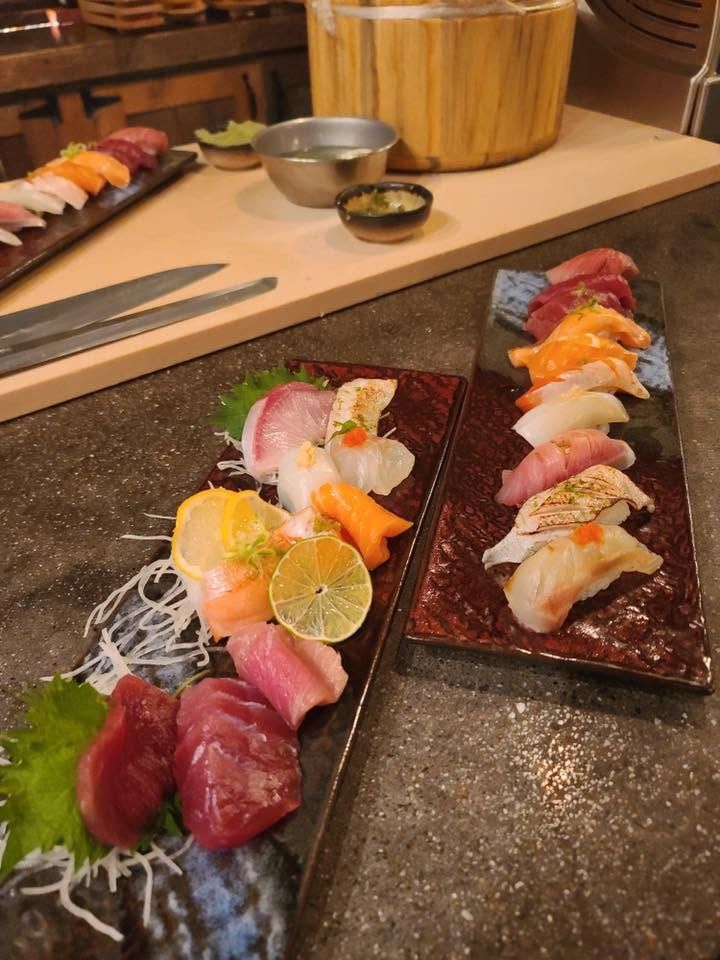 Two plates of assorted sushi with chopsticks on a restaurant counter