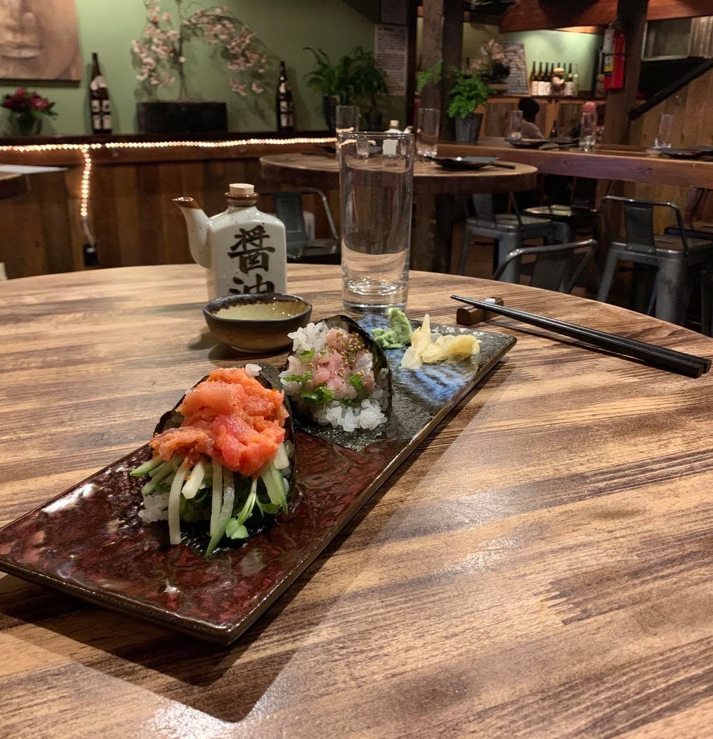 Sushi platter with salmon rolls and a glass of water on a wooden table in a cozy restaurant