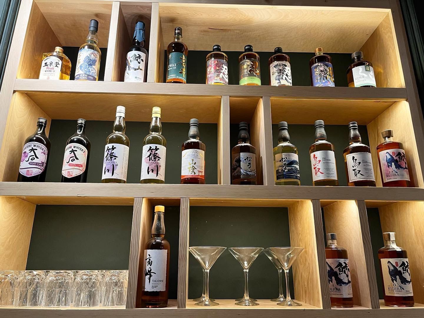 Wooden shelves stocked with assorted beer bottles and glasses in a bar display