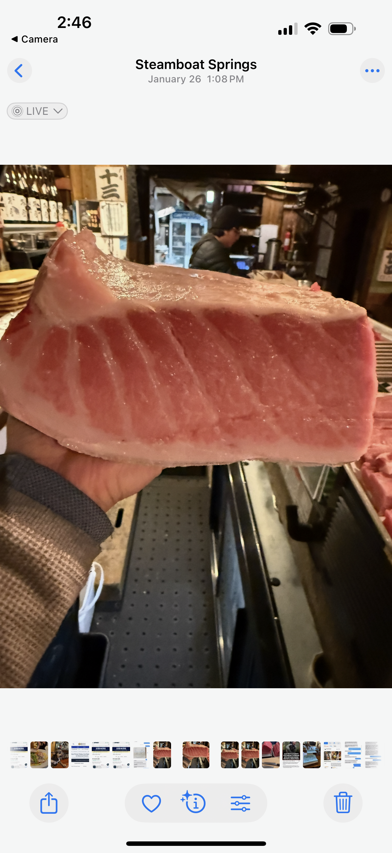 Large slab of pink raw meat displayed on a hand inside a butcher shop corridor