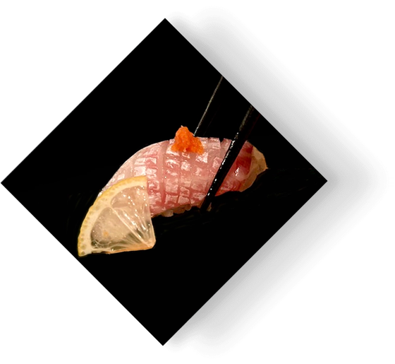 Sushi nigiri with salmon and lemon wedge on a black square plate