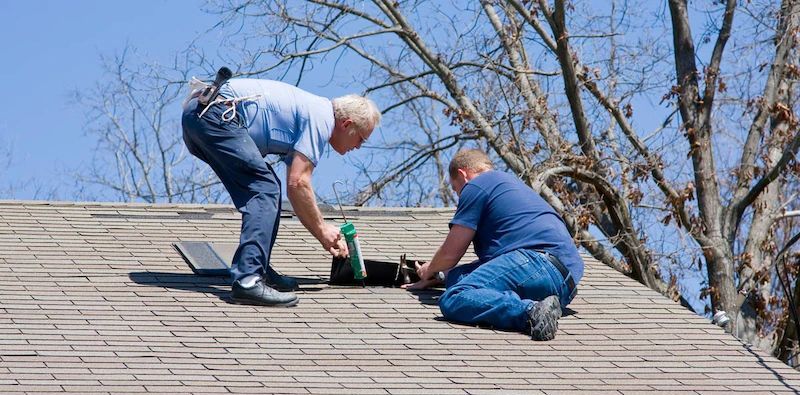 Two Men Are Working on the Roof of a House — Cairns Roofing Contractors Pty Ltd in Bungalow, QLD