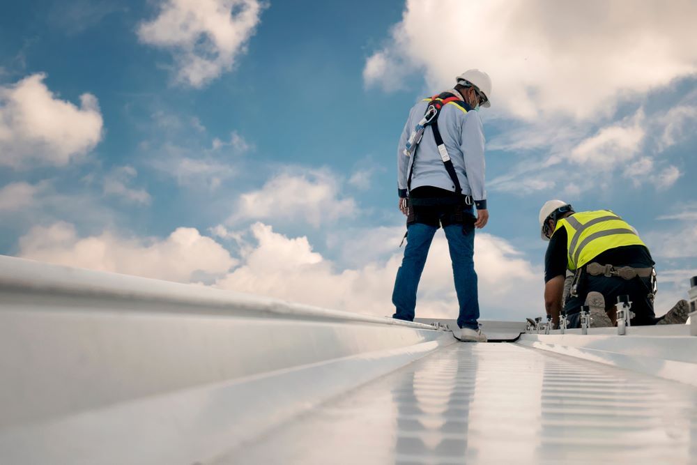 Two Construction Workers Are Working on a White Roof — Cairns Roofing Contractors Pty Ltd in Bungalow, QLD