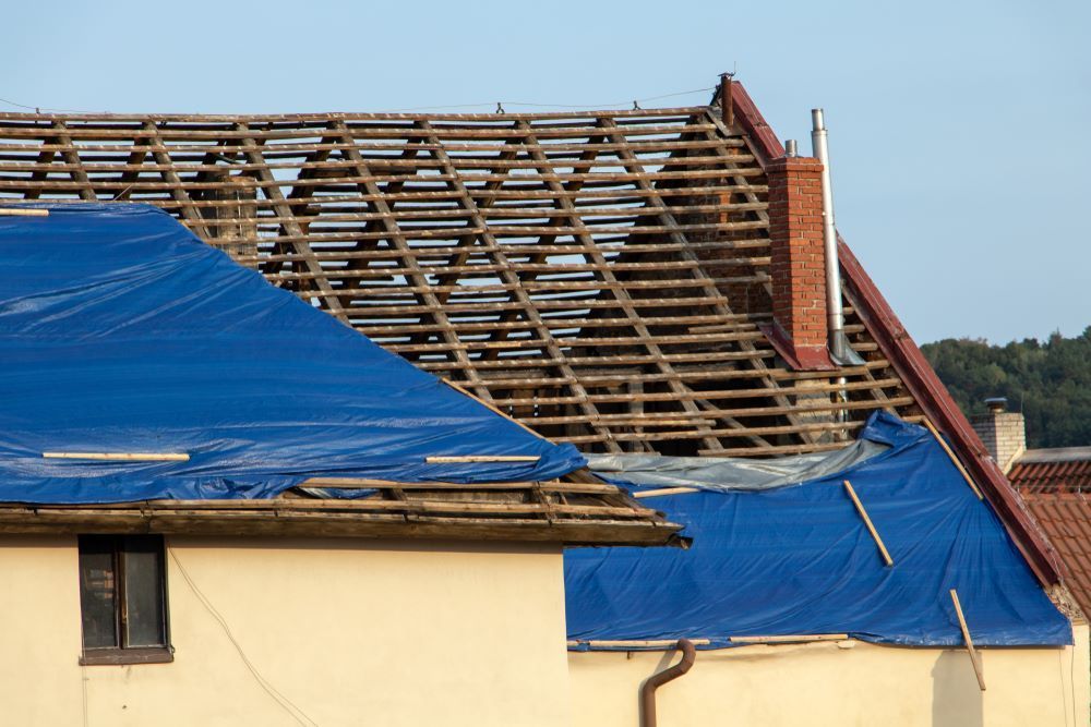 The Roof of a House is Being Covered With a Blue Tarp — Cairns Roofing Contractors Pty Ltd in Bungalow, QLD