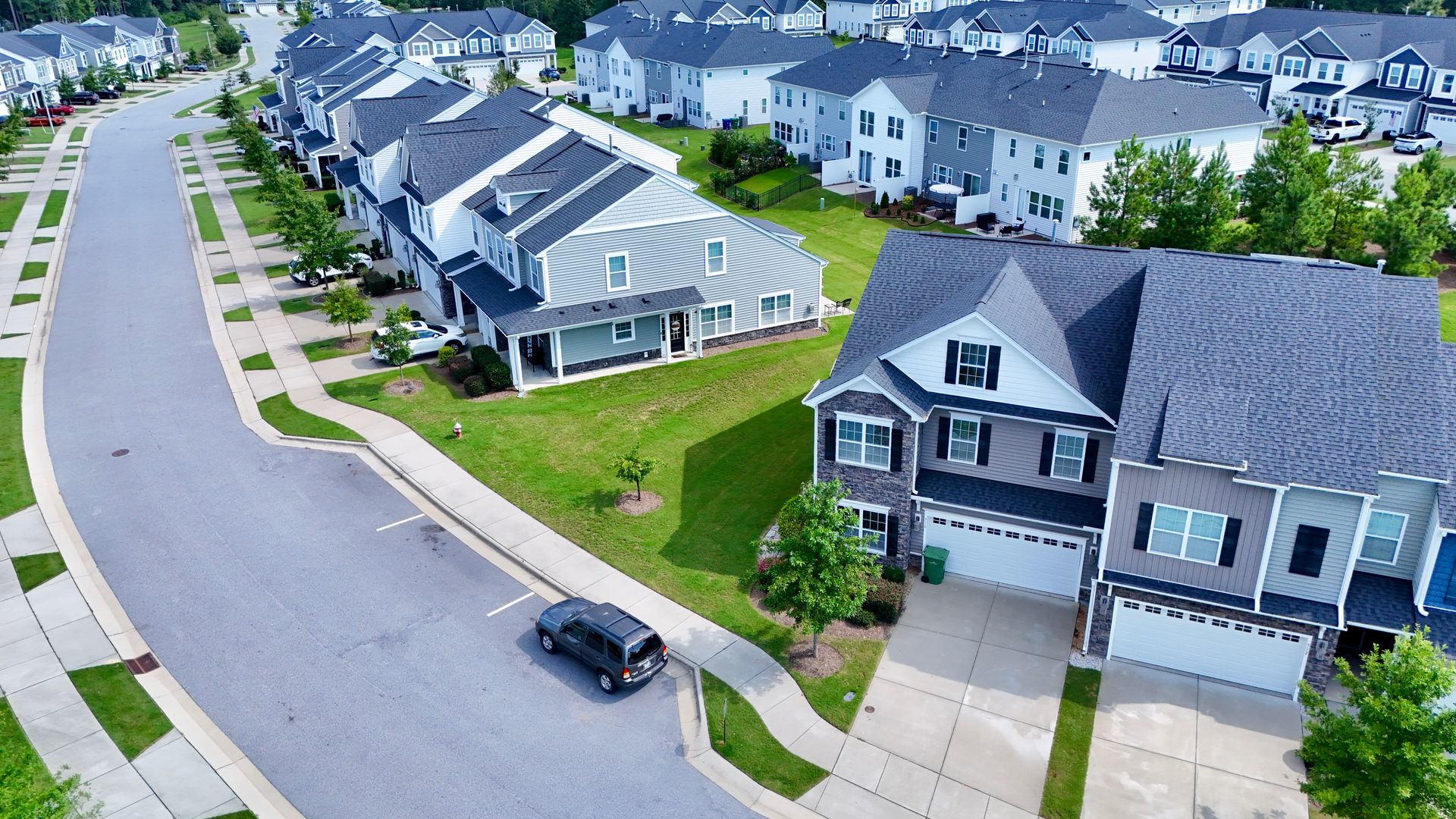 Aerial view of a suburban neighborhood with houses, a street, and a parked car.