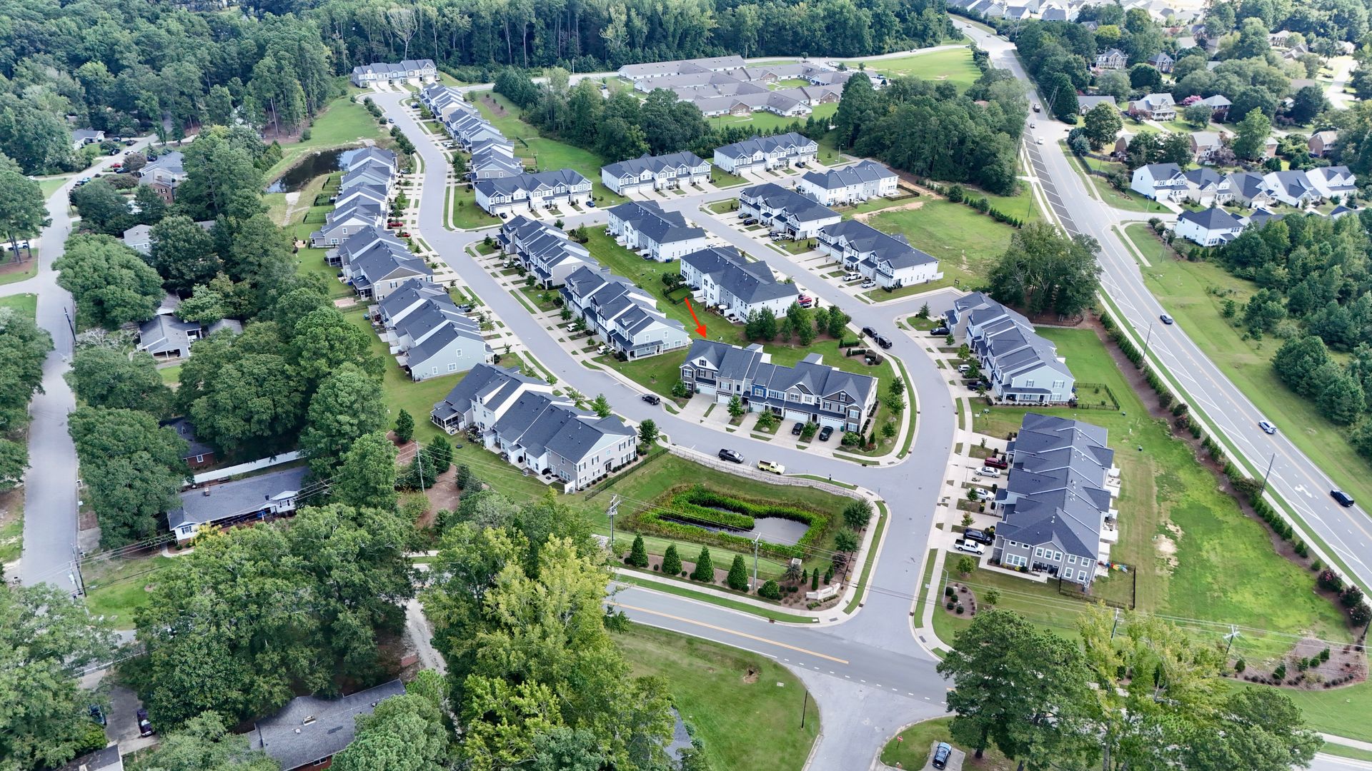 Aerial view of a residential neighborhood with rows of houses, roads, and surrounding trees.