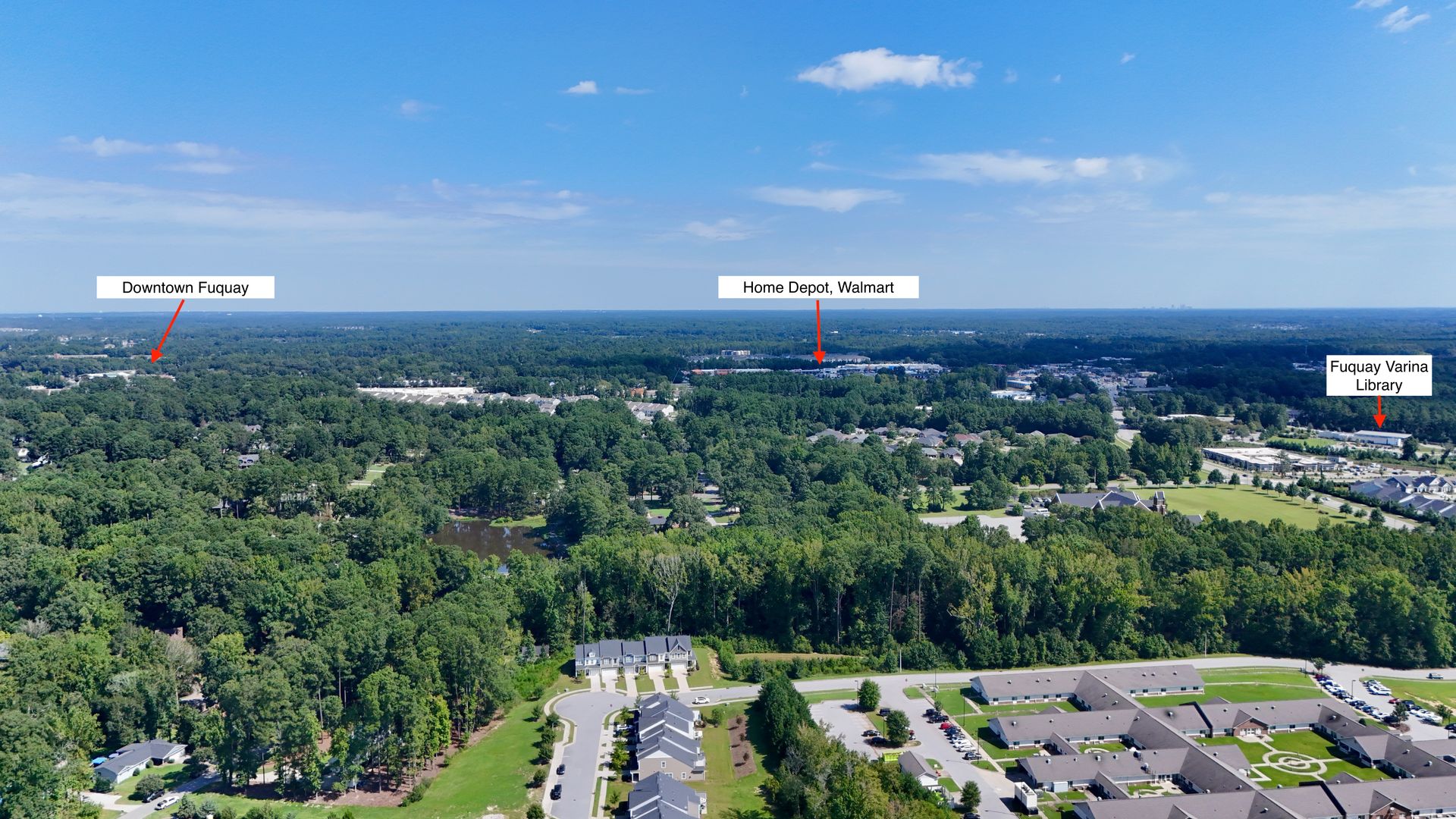Aerial view of a town with trees, labeled buildings, and a clear blue sky.