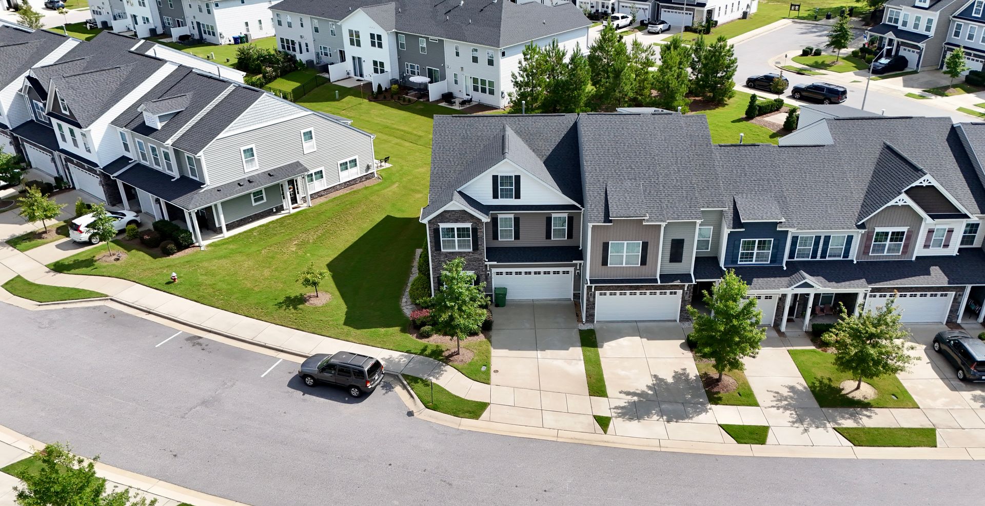 Aerial view of houses in a residential neighborhood with green lawns and driveways.