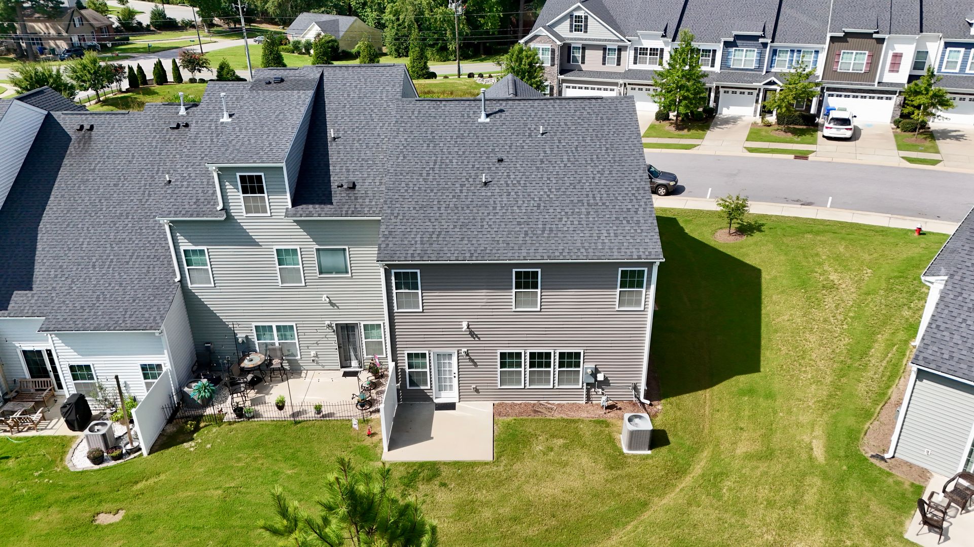Aerial view of townhomes with gray siding, gray roofs, and green lawns.