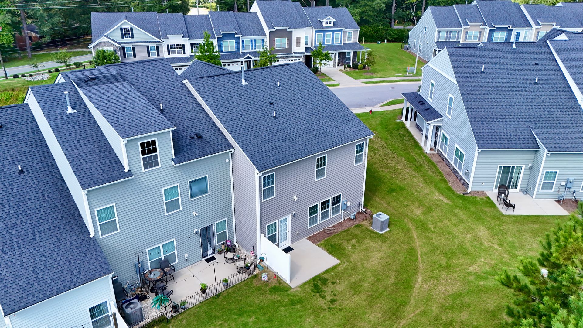 Aerial view of suburban homes with gray and blue siding, and dark gray rooftops.