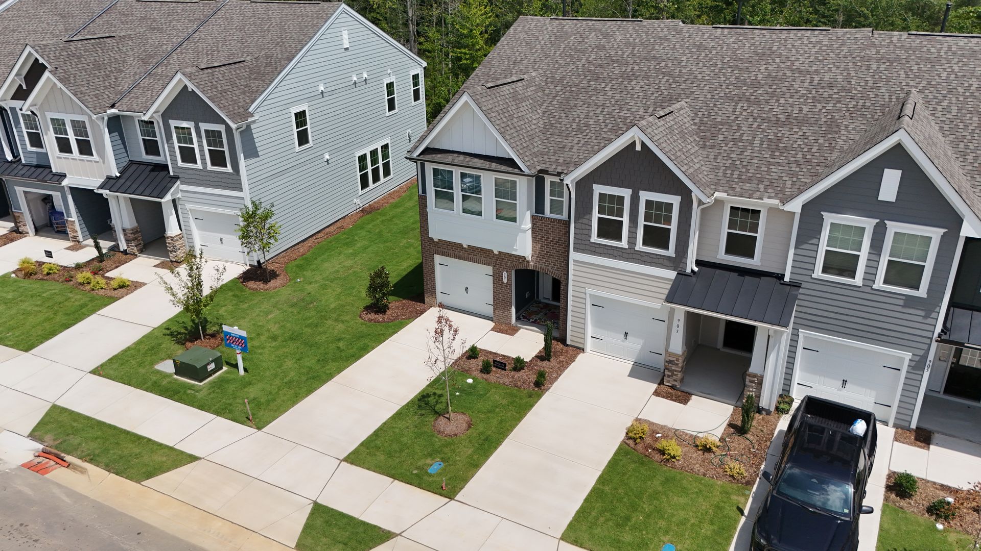 Row of newly built townhomes with green lawns and driveways.